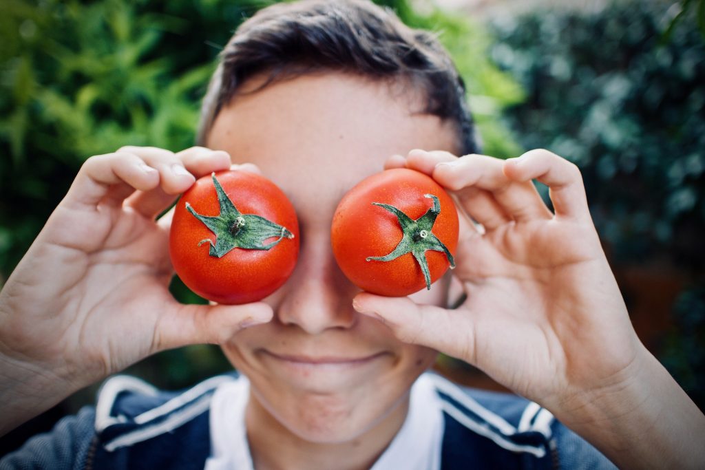 Kid playing with tomatoes
